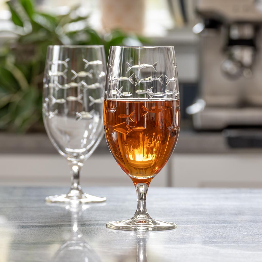 Rolf Glass School of Fish 16oz Footed Iced Tea Glass full of iced tea on kitchen counter