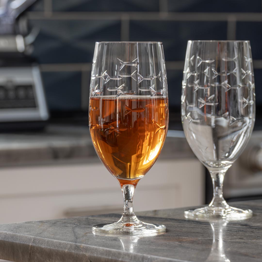 Rolf Glass School of Fish 16oz Footed Iced Tea Glass full of iced tea on kitchen counter