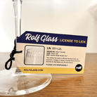 Rolf Glass wine glass with a humorous 'License to Lick' label on a wooden surface.
