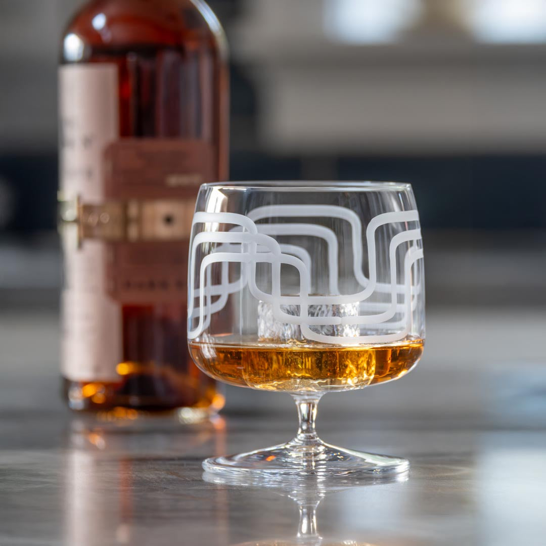 Mid Century Modern 17oz Footed Rocks Cocktail Glass with a bottle of Basel Haden