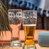 Rolf Glass Numbskulls 20oz Large Pilsner Beer Glass skull wearing beats head phones and skull wearing beanie on the patio