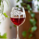 Rolf Glass Palm Tree 18oz Red Wine Balloon Glass full of red wine on a desk