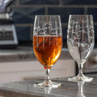 Rolf Glass School of Fish 16oz Footed Iced Tea Glass full of iced tea on kitchen counter