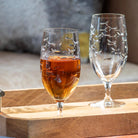 Rolf Glass School of Fish 16oz Footed Iced Tea Glass full of iced tea on coffee table