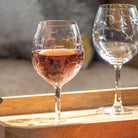 Rolf Glass School of Fish 18oz Balloon Red Wine Glass on a wood tray