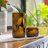 Rolf Glass Twice Around Citrus Garden Mocha 13oz Pitcher and 2" sipper glasses set of 3 on a desk